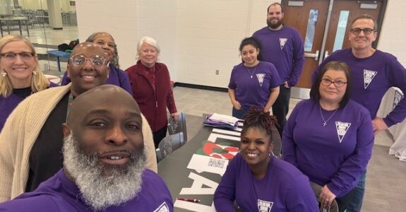 A group of individuals take a selfie around a table