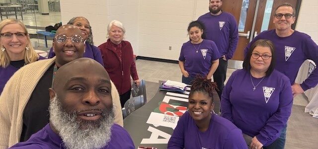 A group of individuals take a selfie around a table