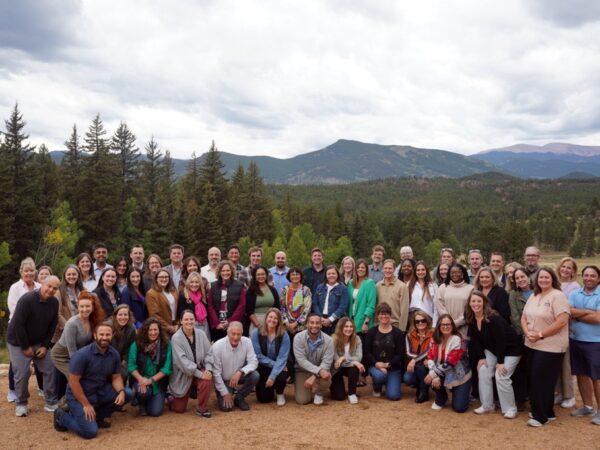 Large group of people pose for a photo, with a mountain in the distance
